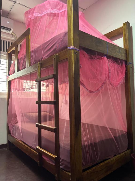 a wooden bunk bed with pink sheets on it at Lake Hostel Anuradhapura in Anuradhapura