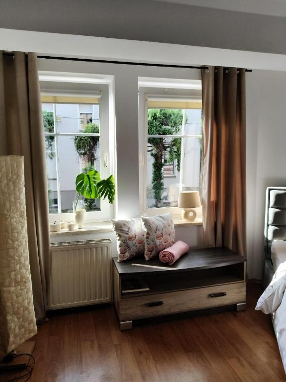 a bedroom with two windows and a bench with pillows at Apartament ANTONIA in Olesno