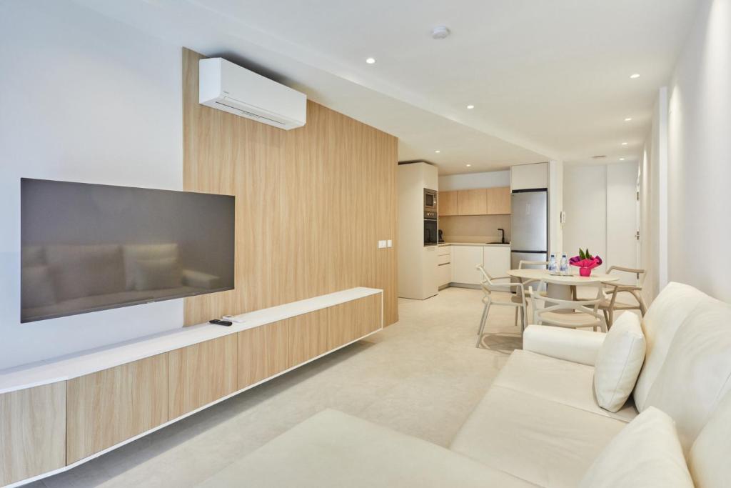 a living room with a large television and a white couch at Silken Atlantis Playa - Holiday Homes in Las Palmas de Gran Canaria