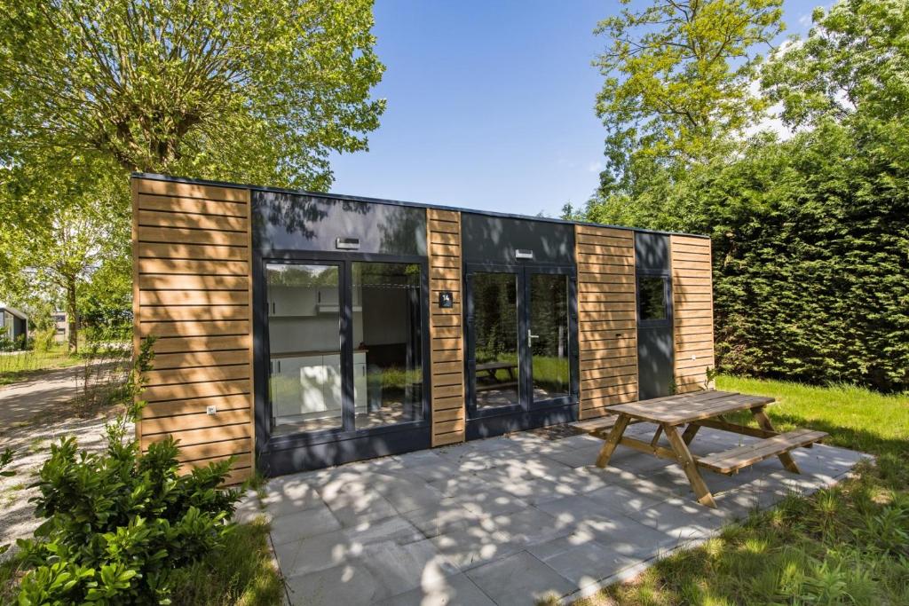 a tiny house with a bench on a patio at Cube I stijlvol en licht 4 persoons chalet in Zennewijnen