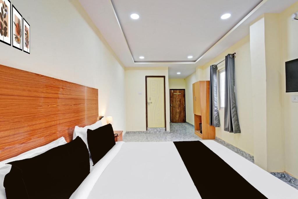 a bedroom with a large bed with a wooden headboard at Hotel O Madlen in Hyderabad