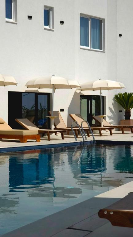 a pool with chairs and umbrellas next to a building at Hotel Zurich in Golem