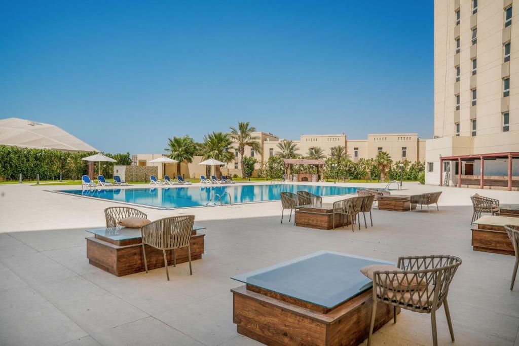 a patio with tables and chairs next to a pool at Premium Four Star Hotel by Blue Collection in Ras al Khaimah
