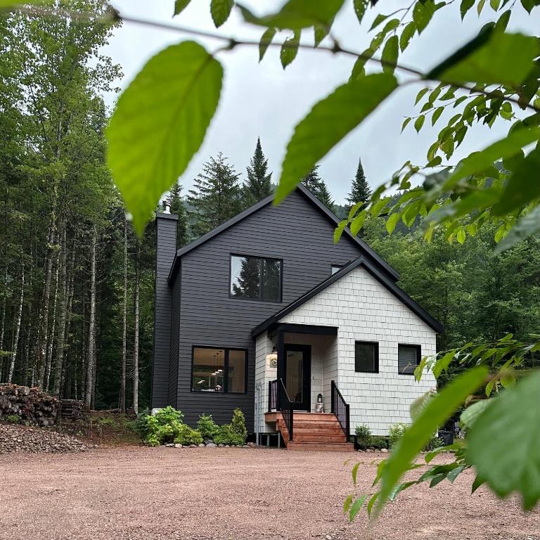 a black and white house in the woods at Chalet Le St-Ray in Saint-Raymond