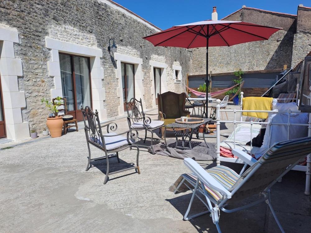 a patio with chairs and a table with an umbrella at la MORINNIERRE in Saint-Jean-de-Beugné
