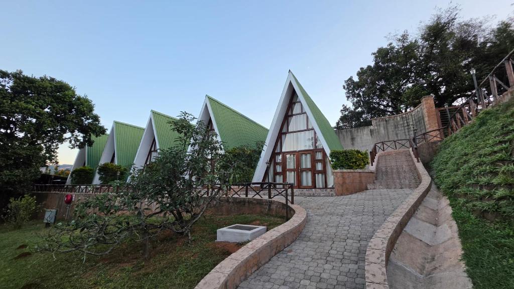 a stone path leading to a building with green roofs at Mvubu Falls Lodge in Lobamba