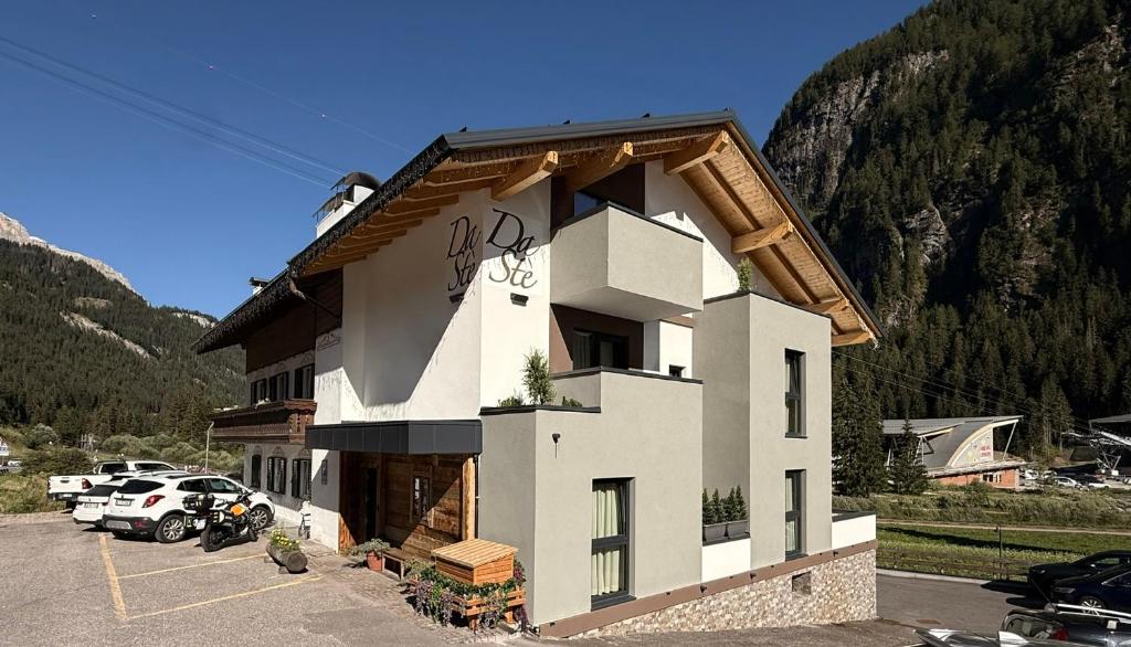 a building in a parking lot next to a mountain at DaSte' ex Villa Ruggero in Campitello di Fassa