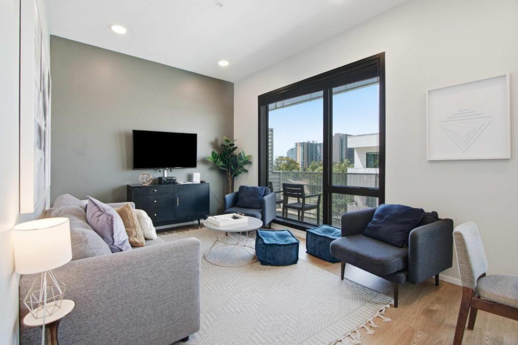 a living room with a couch and chairs and a tv at Illume 303 in Nashville