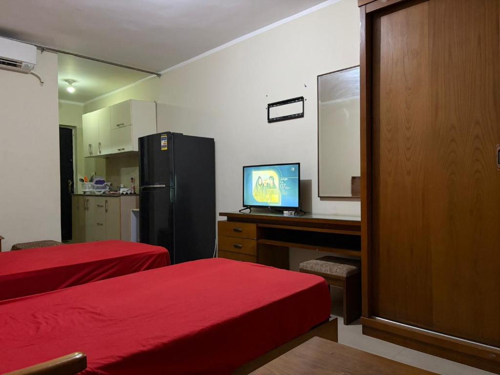 a room with two beds and a desk with a television at Pool view studio apartment, Aqua View Resort, North coast in El Alamein