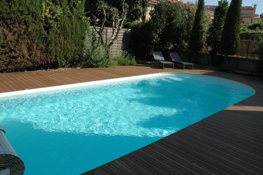 a blue swimming pool with two chairs on a wooden deck at Cabesthotes in Cabestany