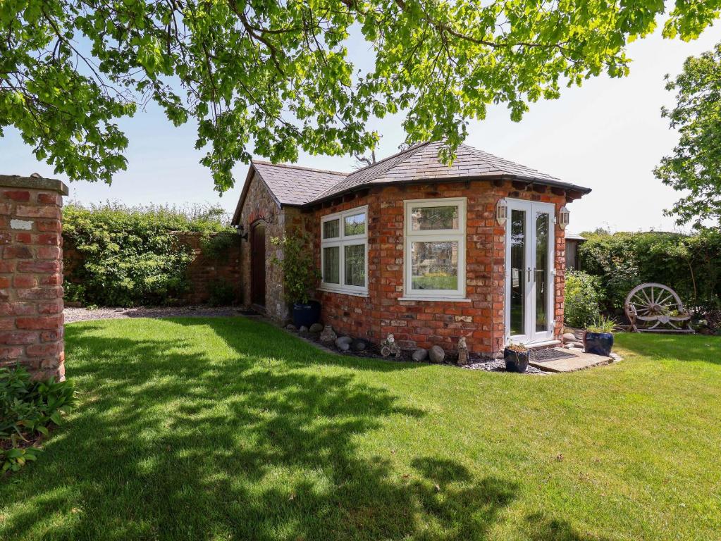 a small brick house with a grass yard at Ty Haf in Mold