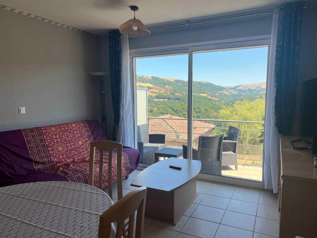 a living room with a bed and a large window at Résidence la Marquise in Trébas