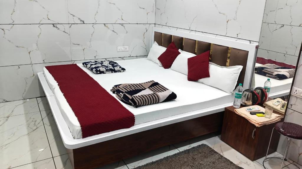 a white bed with red and black pillows on it at Hotel DIVYA DARSHAN in Ujjain