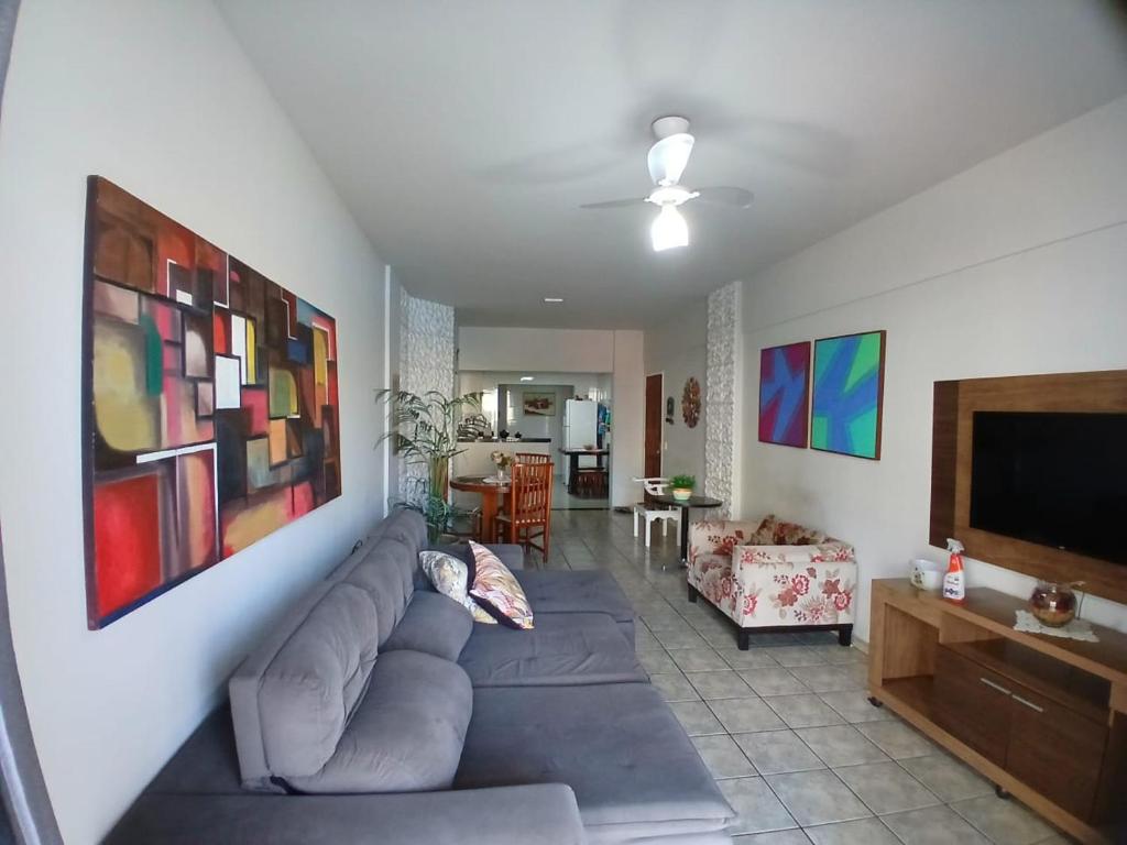 a living room with a couch and a flat screen tv at Apartamento 3 Quartos, Churrasqueira, Vista Mar, Varanda, 5 min da praia in Guarapari