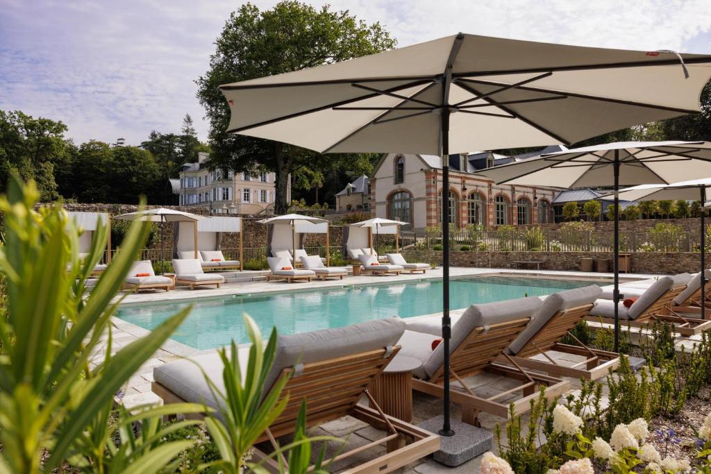 a swimming pool with lounge chairs and umbrellas at Domaine de Locguénolé & Spa - Relais & Chateaux in Kervignac
