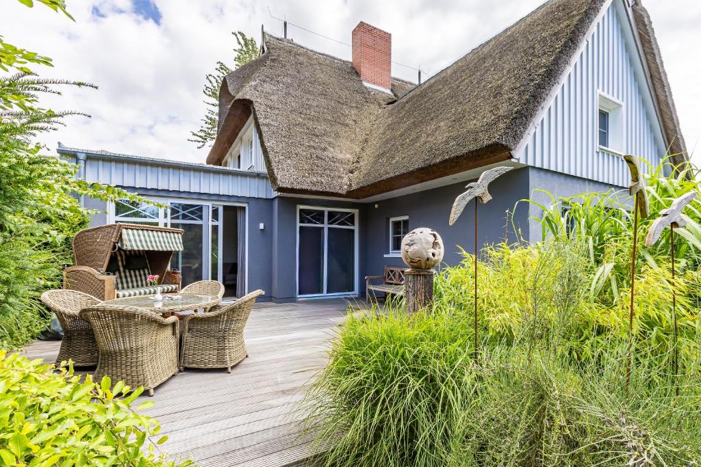 a deck with wicker chairs and a blue house at Freischwimmer in Wieck