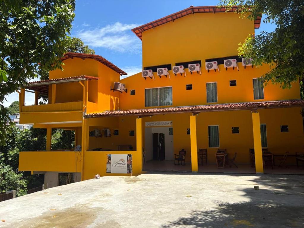 a yellow house with chairs on the balcony at Uma Janela Para o Sol in Morro de São Paulo
