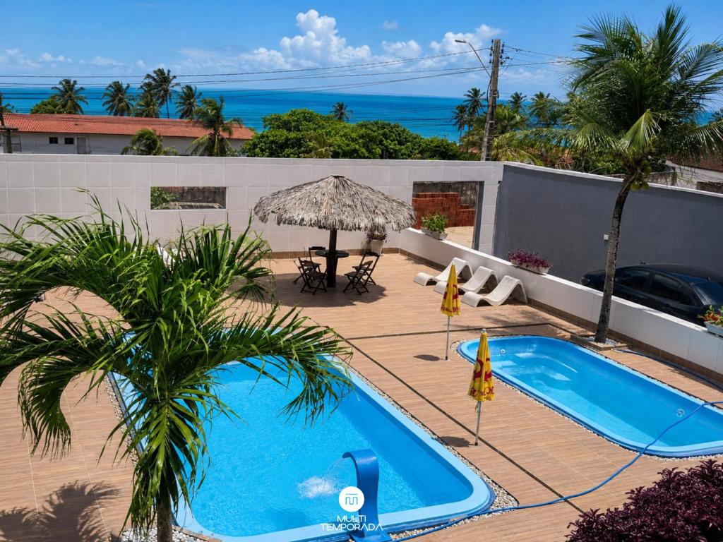 a swimming pool on a patio with a view of the ocean at Pousada On the Beach - Aquiraz/CE in Aquiraz