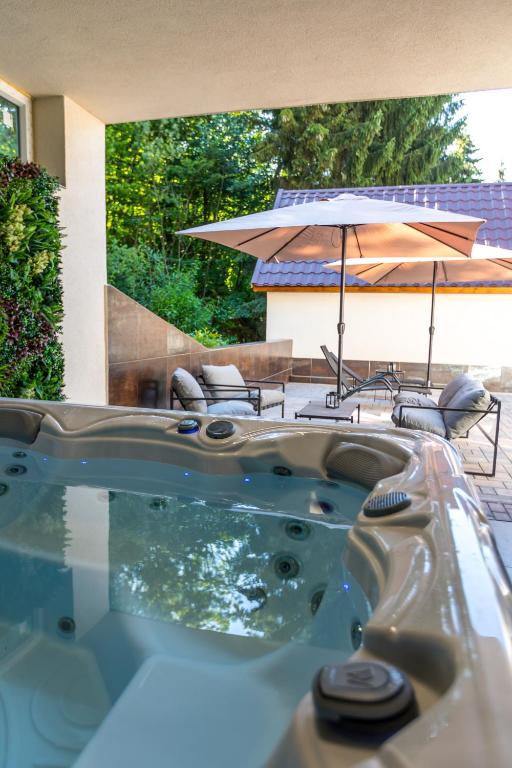a jacuzzi tub in a yard with an umbrella at Fakanalas Fogadó in Pásztó
