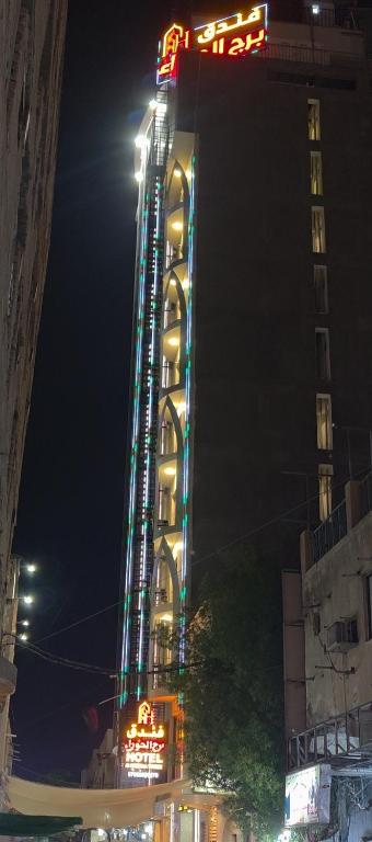 a tall building with lights on it at night at فندق برج الحوراء ع in Karbala