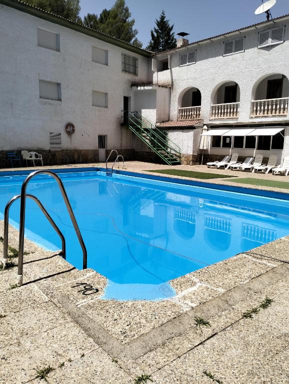 a large blue swimming pool in front of a building at Pensión Rural Arroyo la Teja in Arroyo Frio