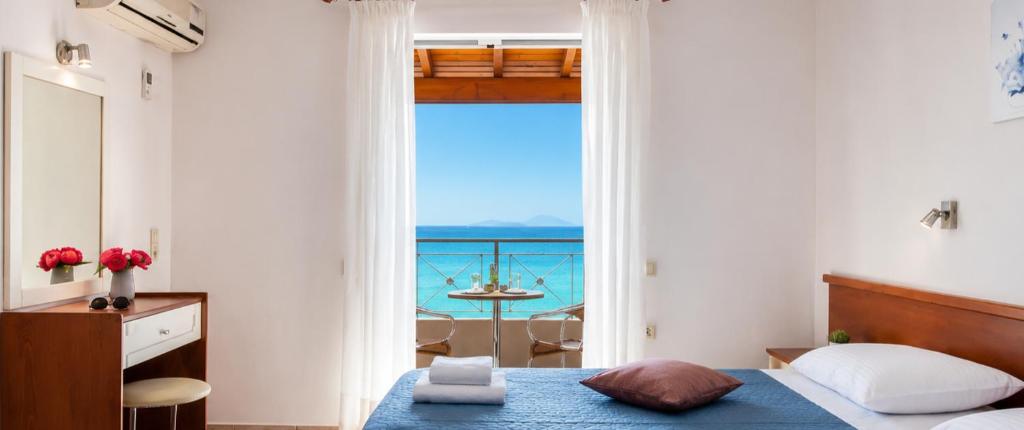 a bedroom with a bed and a view of the ocean at Corfushell Resort Hotel apart in Barbati