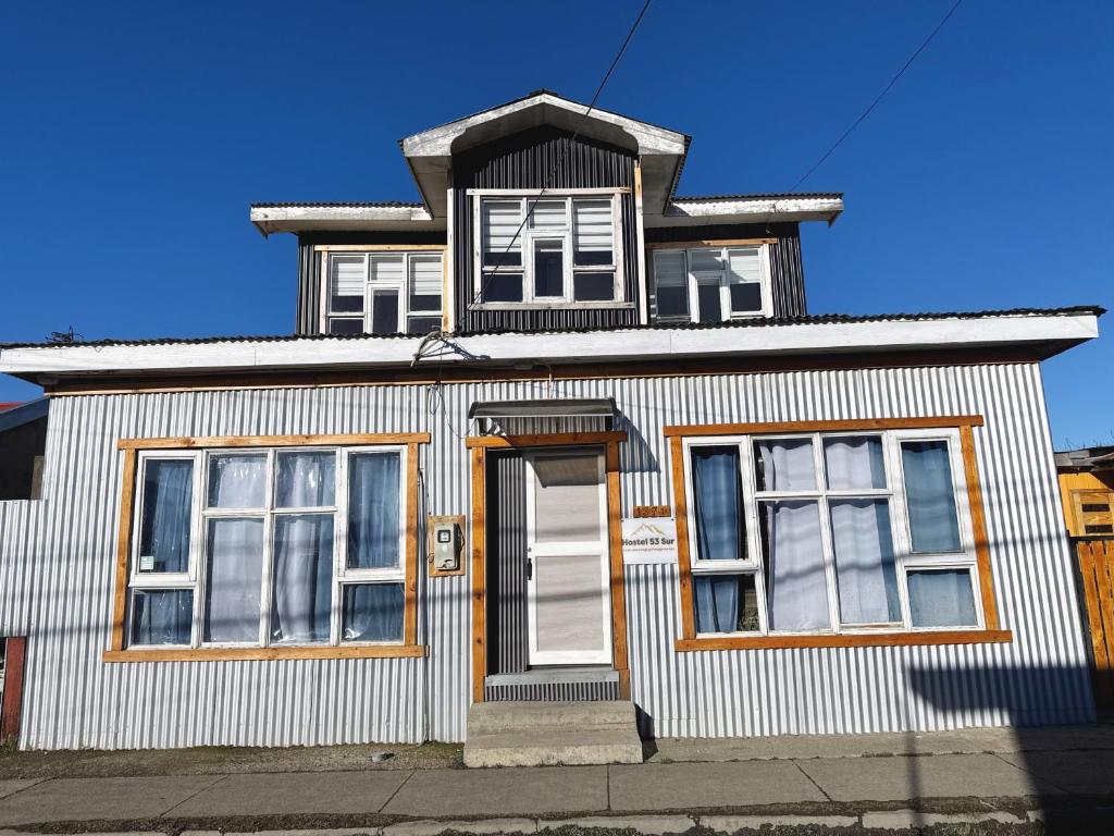 a white house with a white door and windows at Hostel 53 Sur in Puerto Natales