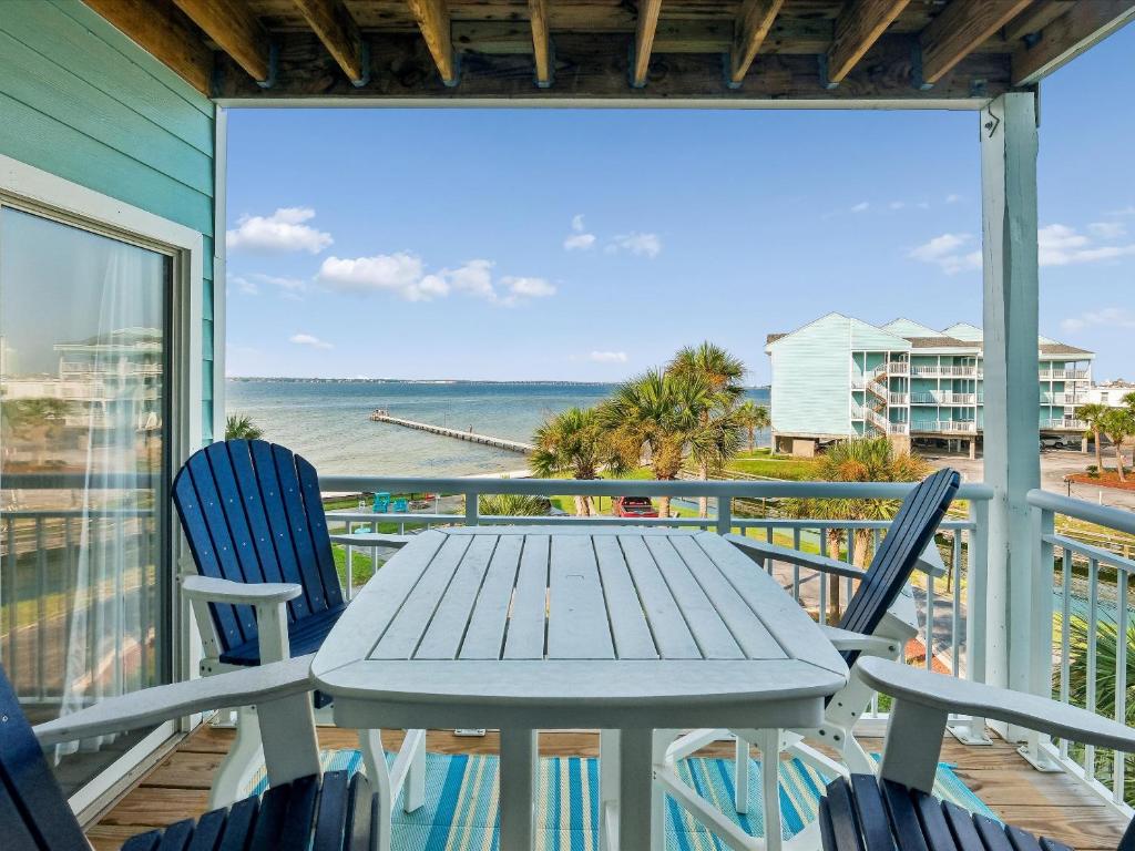a table and chairs on a balcony with a view of the ocean at Baywatch #C5 in Pensacola Beach