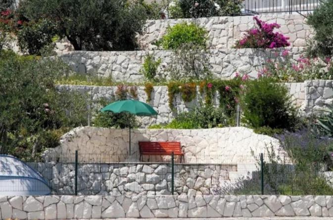 a bench with an umbrella sitting on a stone wall at Dobrila in Slano