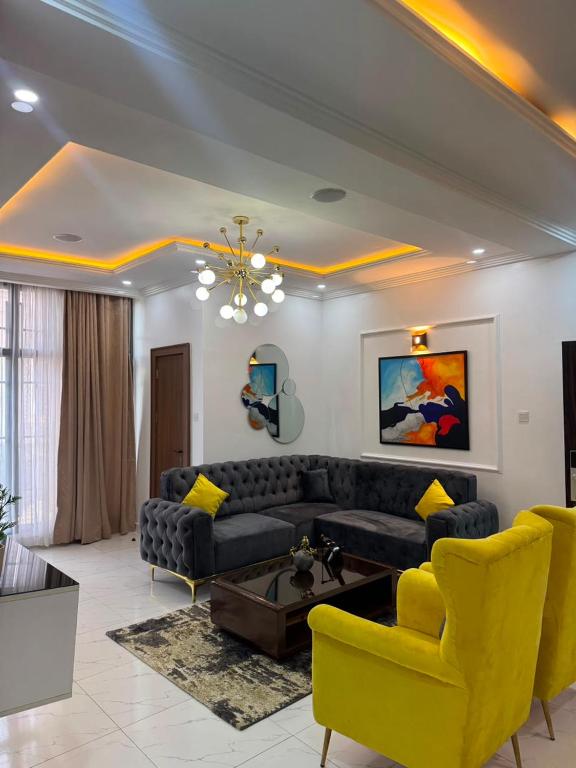 a living room with a black couch and yellow chairs at Verse Living in Abuja