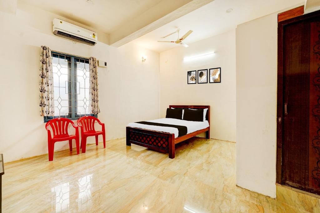 a bedroom with a bed and two red chairs at Hotel O Sky Blue Residency in Chennai