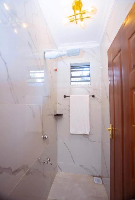 a white bathroom with a shower and a ceiling at Elazoh Apartments in Kisumu