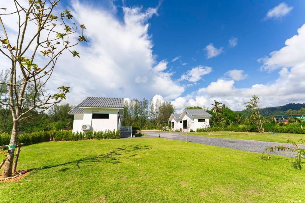 a house with a green lawn and a road at NS Khaolak Resort in Khao Lak