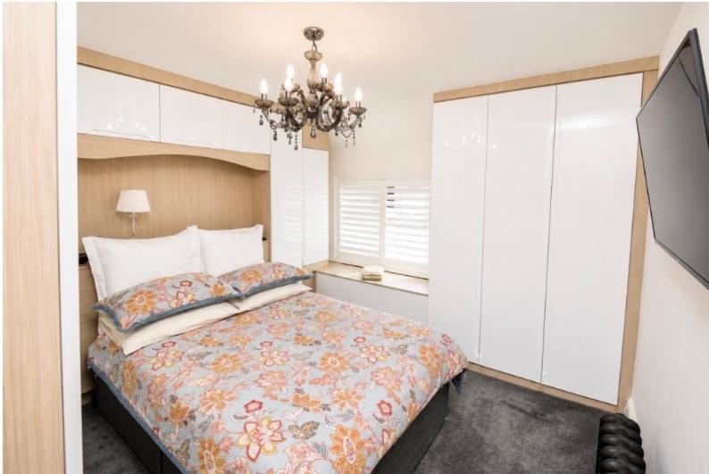 a bedroom with a bed and a chandelier at Lennon cottage in Hale