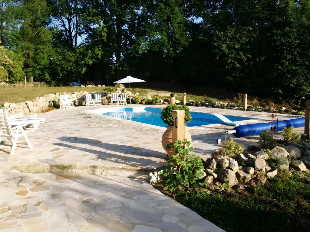 a swimming pool in a yard with chairs and an umbrella at Villa Felinas in Ahun