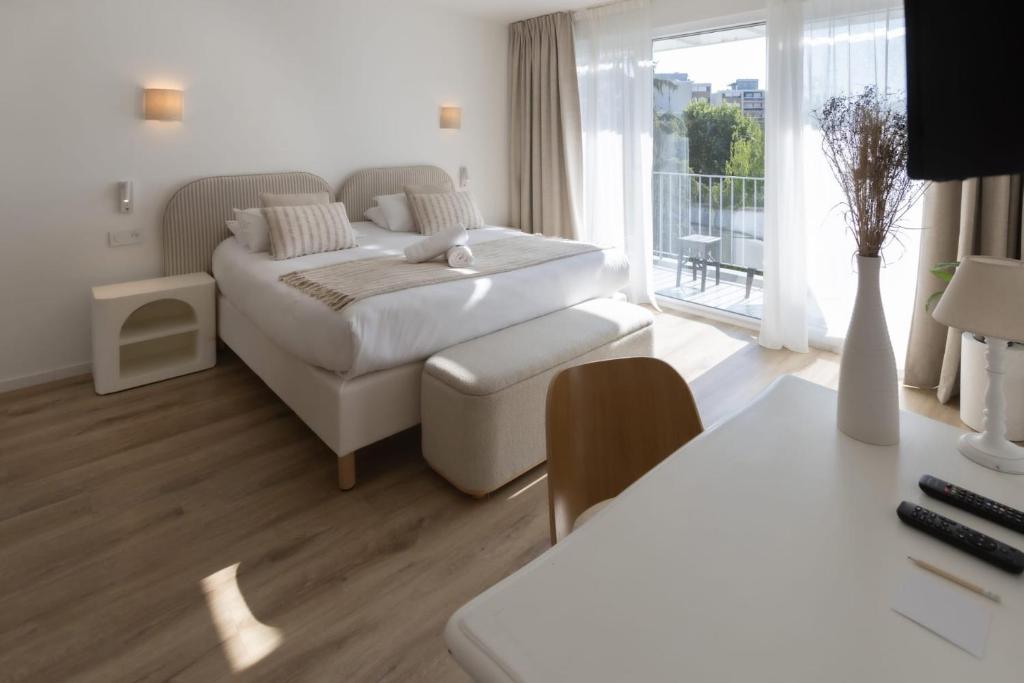 a white bedroom with a bed and a balcony at Hotel Maison Forge - Ex Hotel ASTORIA- Saint Etienne-Centre des Congrès- in Saint-Étienne