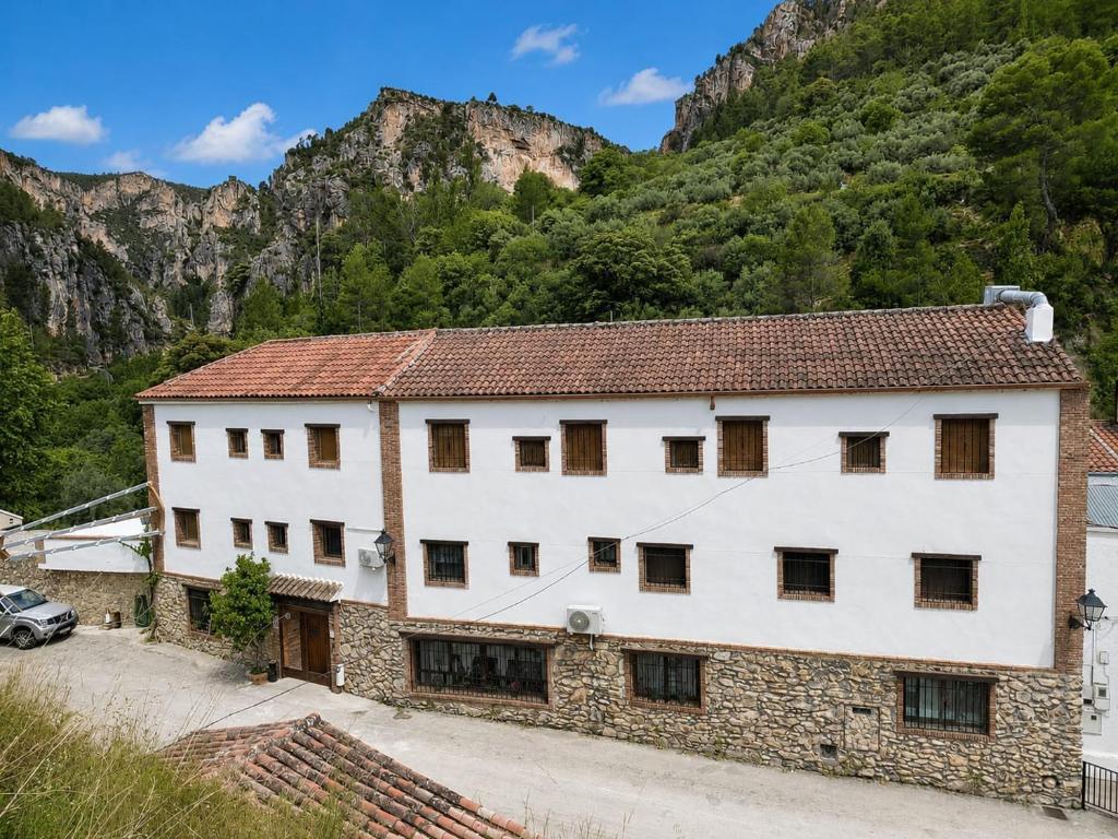 a large white building with mountains in the background at Hotel Spa Venta Ticiano in Yeste