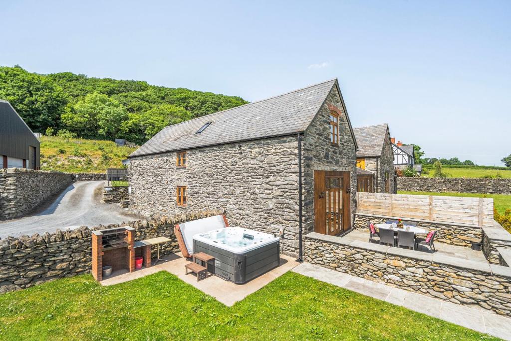 ein Steinhaus mit Grill und Whirlpool in der Unterkunft Hay Store in Corwen