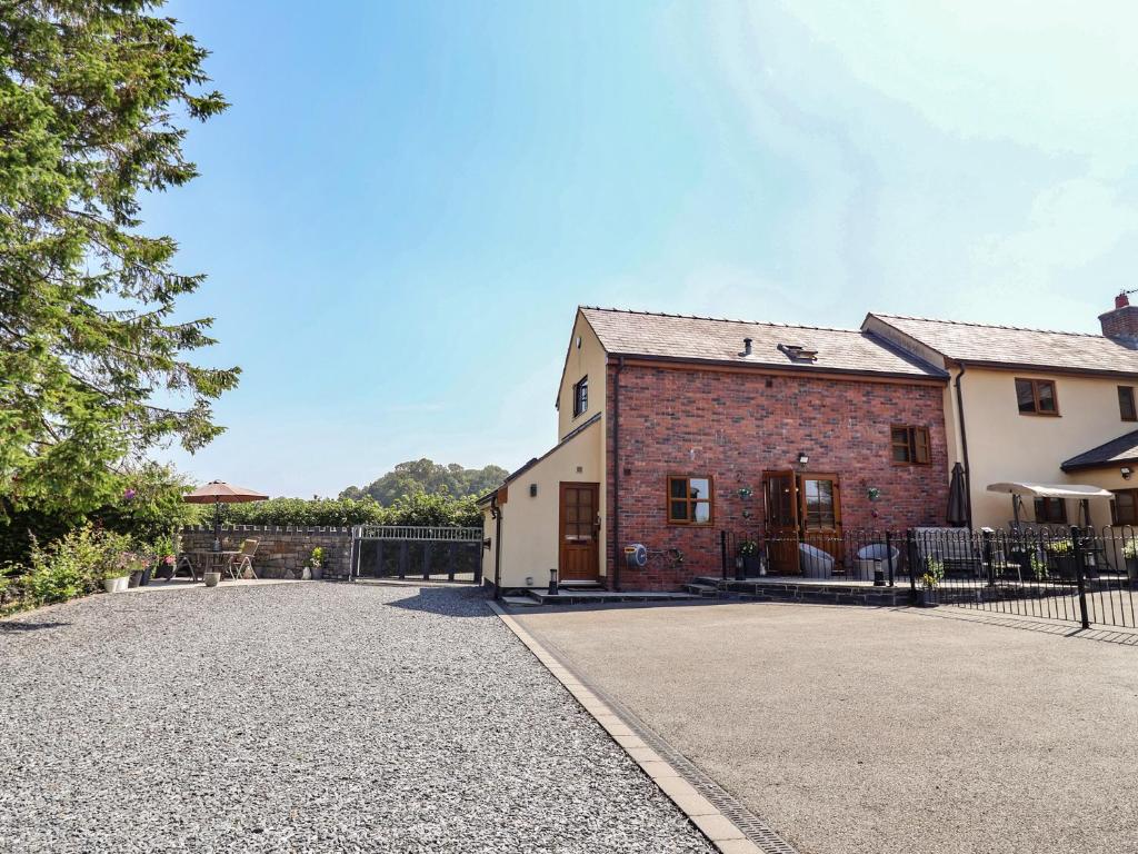 an old brick building with a fence in front of it at Ash Farm Cottage in Holywell