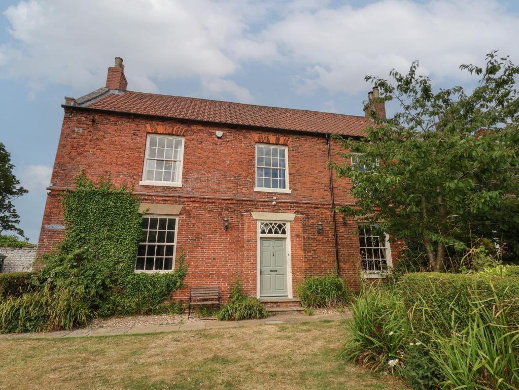 an old red brick house with a white door at Reighton House in Filey