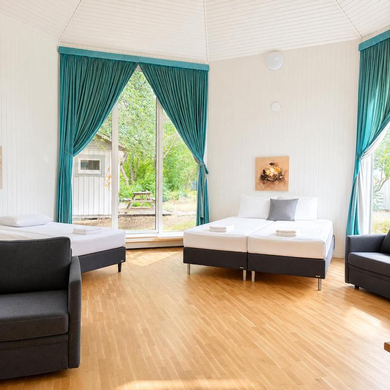 two beds in a room with blue curtains at Bokloster Longstay in Märsta