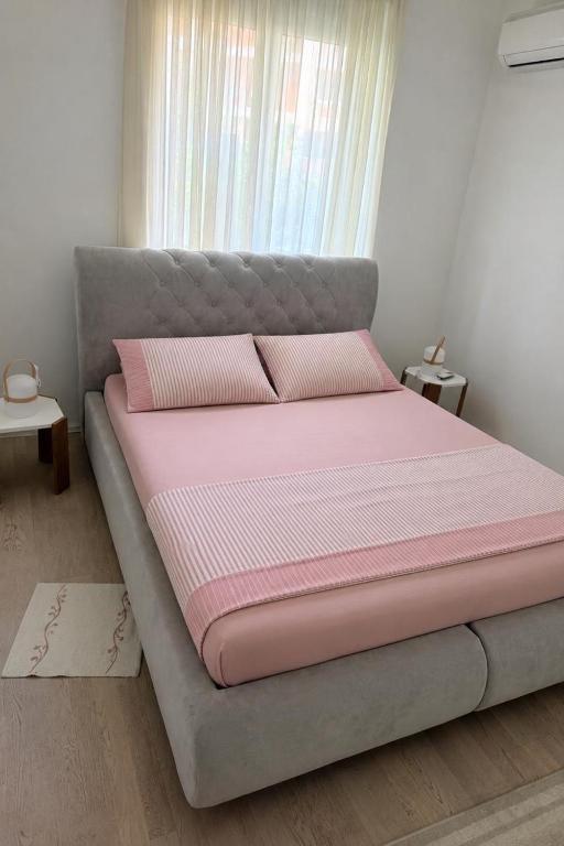 a bed with pink sheets and pillows in a room at Sun House in Kumbor