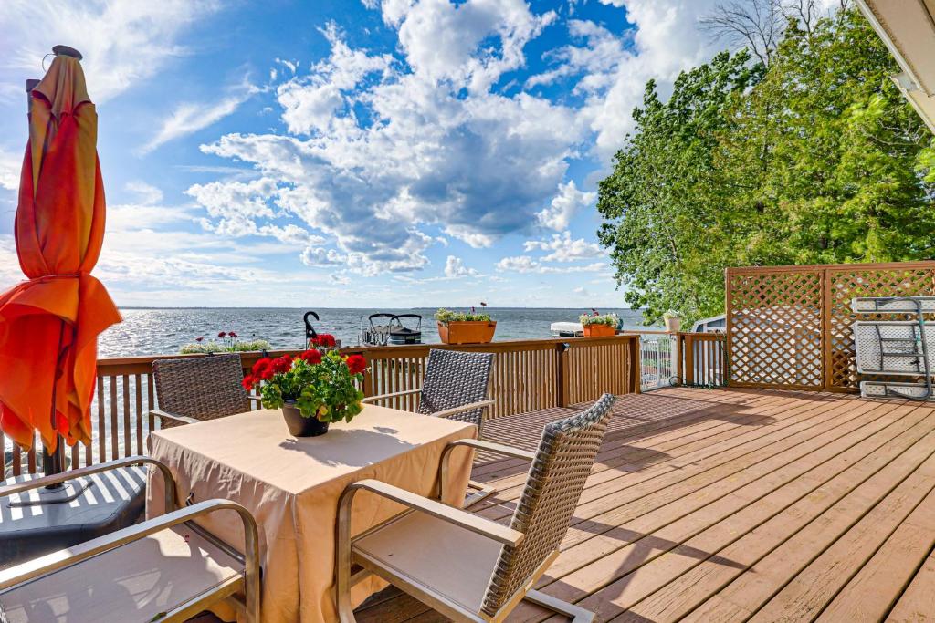 a wooden deck with a table and chairs and the ocean at Sunset Views & Deck: Lake Champlain Cottage! in Swanton