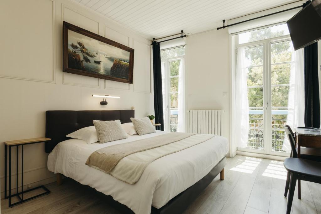 a bedroom with a large bed and a large window at Hotel de Paris in La Rochelle