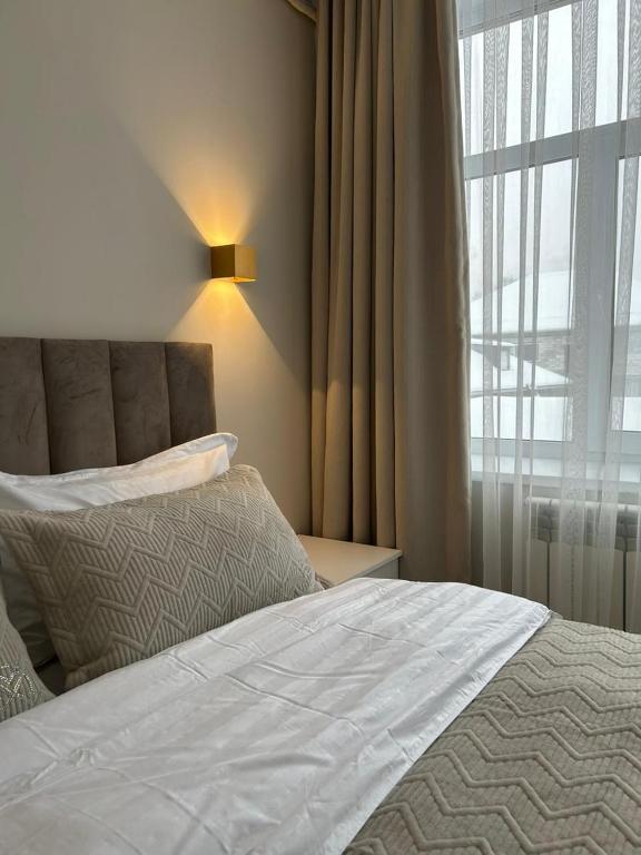 a bedroom with a white bed and a window at Verde Hotel in Semey