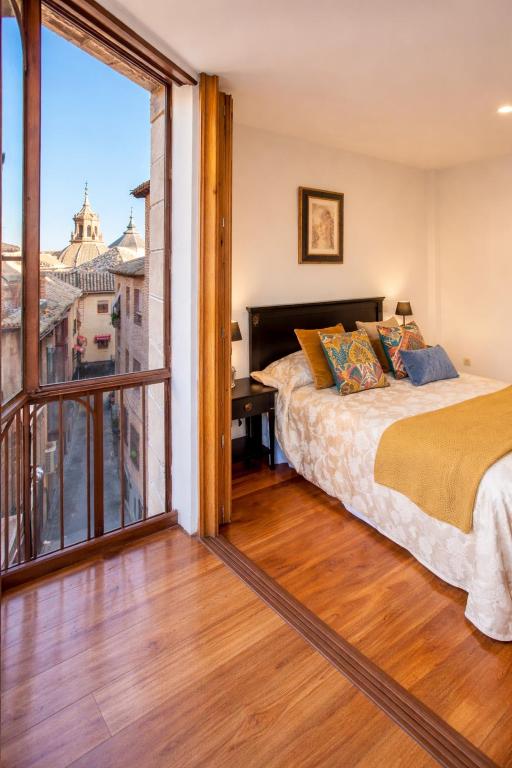 a bedroom with a bed and a large window at Smartmonki Sinagoga entre la Catedral y Zocodover in Toledo