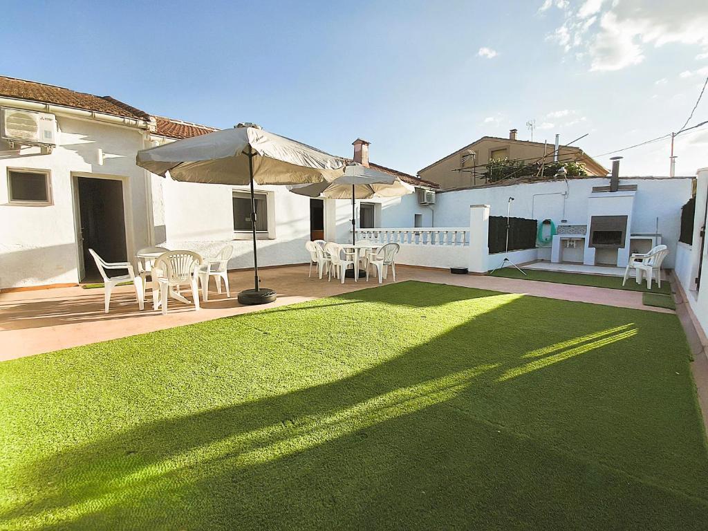 a patio with an umbrella and a lawn at Alojamientos El Pardal in Molinicos
