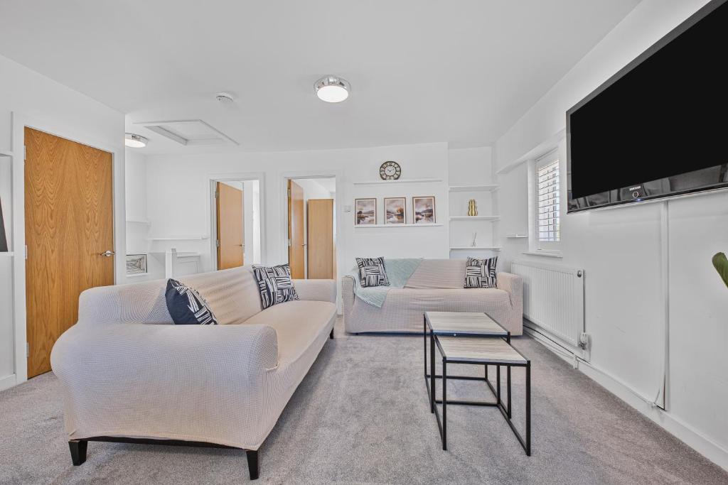 a living room with white furniture and a flat screen tv at 2 Bed Flat 10mins Heathrow 1 Parking EV in Hanworth