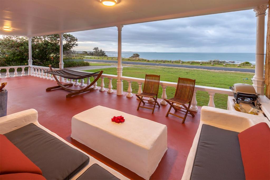 a porch with chairs and a couch and a table at Seascape Beach House in Minnie Water