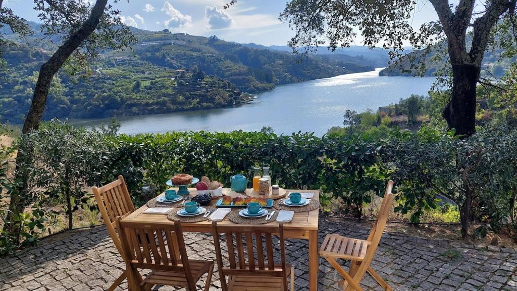 a wooden table with chairs and a view of a river at Casas de Mirão in Baião